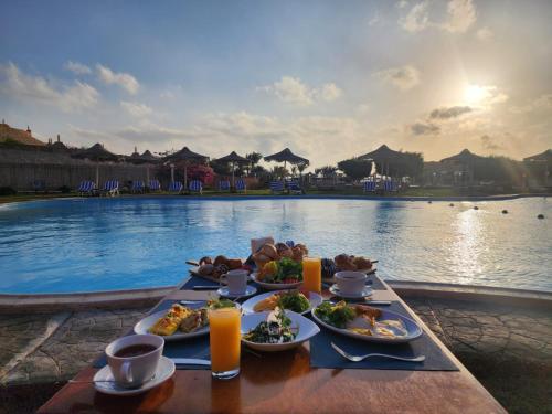 a table with plates of food next to a swimming pool at Fanar Hotel in Ain Sokhna