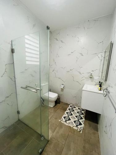 a bathroom with a shower and a toilet and a sink at Seascape Modern Accomodation Near CLUB MED ALBION in Albion