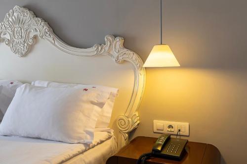 a bed with a pillow and a phone on a night stand at Hotel Beyond in Izmir