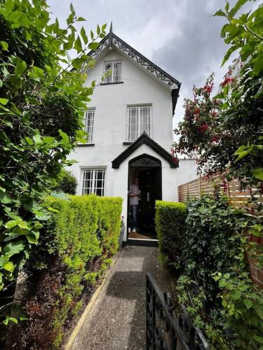 a white house with a black door and bushes at Stunning Georgian Town house with Open Fire, Piano & Games Room in Topsham