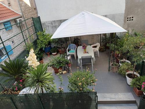 an outdoor patio with a white umbrella and plants at Cozy Studio Apartments with Terrace Near Kaštela Promenade in Kaštela