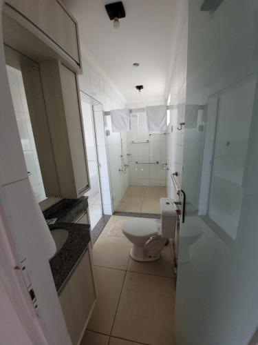 a white bathroom with a toilet and a sink at Hotel Globo in Cianorte