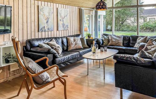 a living room with a black leather couch and a table at Stunning Home In Væggerløse With Sauna in Marielyst