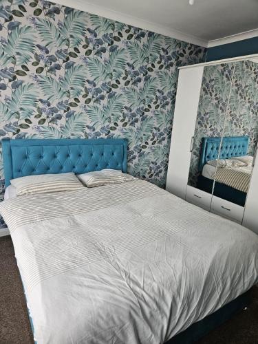 a bedroom with a bed with a blue head board at Large Bungalow to sleep up to 8 in Slough