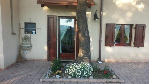 a tree in front of a house with flowers at Le Querce in Ancona