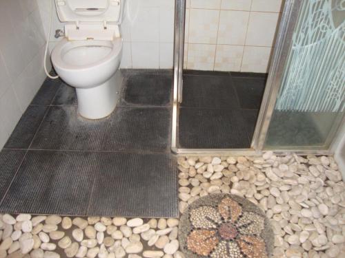 a bathroom with a toilet and rocks on the floor at Gusti Home Stay Ubud in Ubud