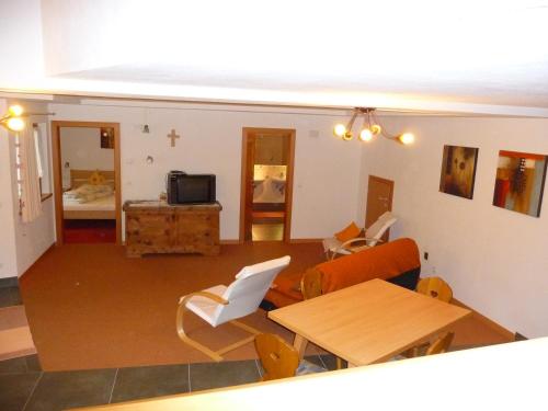a living room with a table and chairs and a television at Gasthof Gemse in Planol