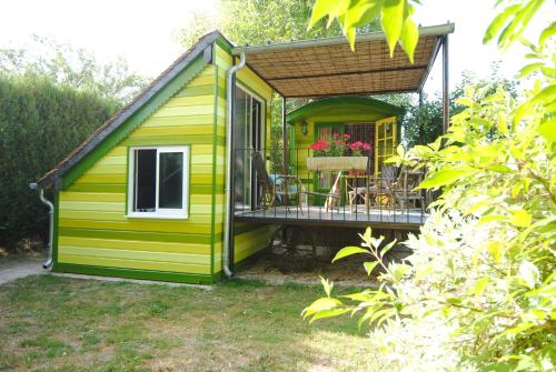 une maison verte et jaune avec une terrasse dans l'établissement Les insolites du Grand Logis, à Marchais