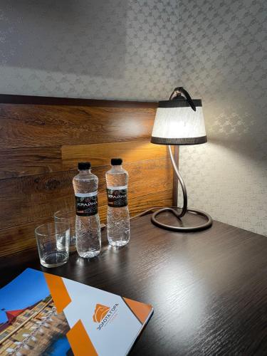two bottles of water sitting on a table with a lamp at Zolota Gora Hotel-Rancho in Uzhhorod