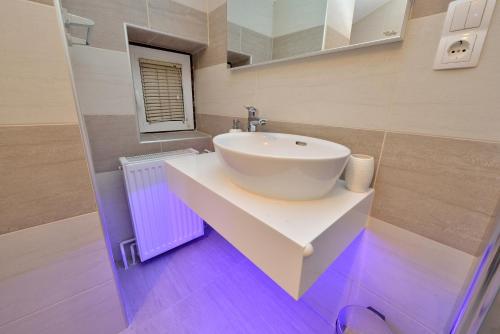 a bathroom with a white sink and a purple floor at Apartments Bracic Spa in Sukošan