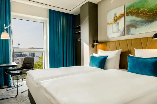 a hotel room with a bed and a desk at Motel One Köln-Altstadt in Cologne