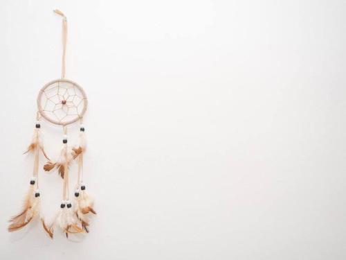 a dream catcher with feathers hanging on a white wall at SibsSanlucar Calma - Centro y Playa - Nuevo in Sanlúcar de Barrameda