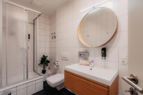 un bagno con lavandino, WC e specchio di Luga Homes - Karli a Lipsia