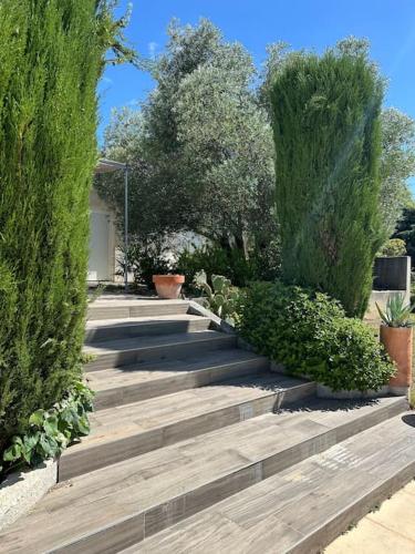 un jardin avec des marches en bois, des arbres et des buissons dans l'établissement Gorgeous 5 bedroom villa with air con, heated pool and garden for 12, à Villemoustaussou