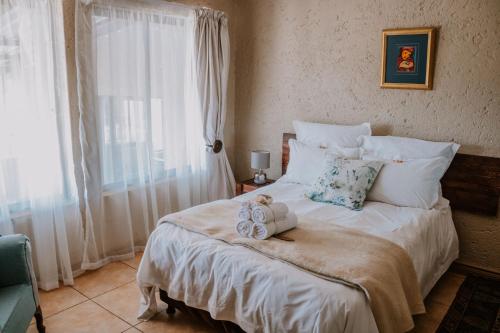 a bedroom with a large bed with towels on it at White Linen Guesthouse in Tierpoort
