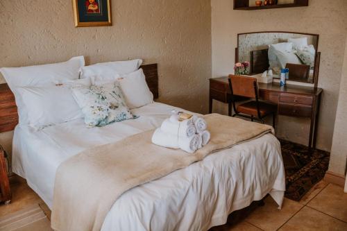 a bedroom with a bed with towels and a desk at White Linen Guesthouse in Tierpoort