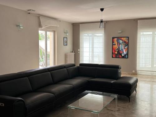 un salon avec un canapé en cuir noir dans l'établissement Gorgeous 5 bedroom villa with air con, heated pool and garden for 12, à Villemoustaussou