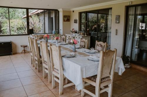 a dining room table with a white table cloth and chairs at White Linen Guesthouse in Tierpoort