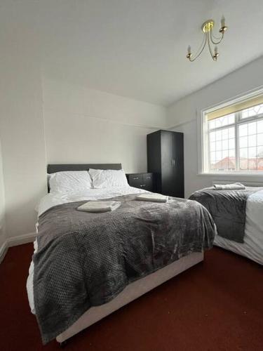 a white bedroom with two beds and a window at West Street House-Furnished Let in Hoyland Nether