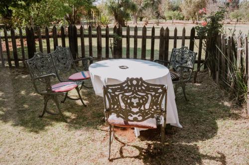 a table and chairs in front of a fence at White Linen Guesthouse in Tierpoort