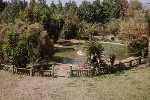 a garden with a fence and a pond at White Linen Guesthouse in Tierpoort