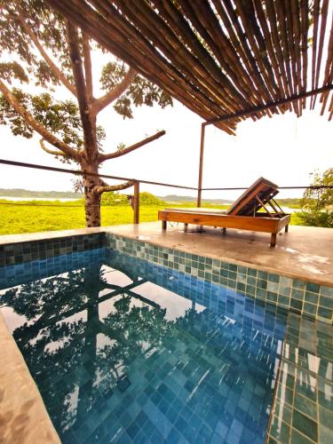 a swimming pool with a bench and a tree at La Purita Ecolodge in The Gap