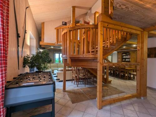 une grande chambre avec un escalier en bois et une table de jeux dans l'établissement Les Bruyères - 15 pers - full nature, à Xonrupt-Longemer