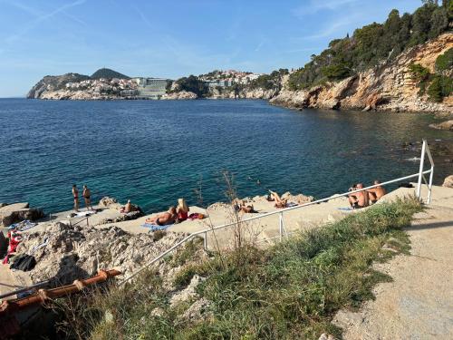 a group of people laying on the beach near the water at Villa Anica Dubrovnik - luxurious with a sea view in Dubrovnik