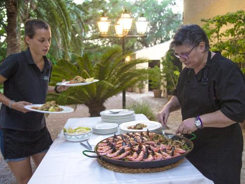 two people standing at a table with a plate of food at Finca Hotel Rural Predio Son Serra in Can Picafort