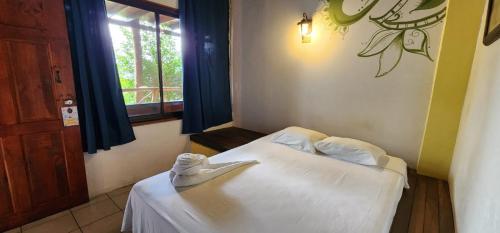 a bedroom with a bed with white sheets and a window at Hostel Plinio in Manuel Antonio