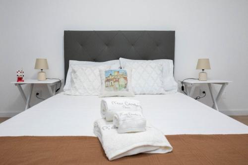 a white bed with two towels on top of it at A Casinha do Canto in Moura