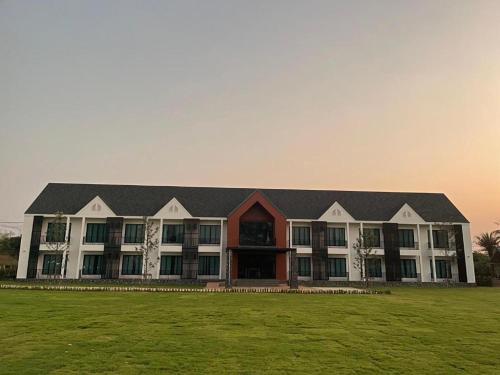 a large building with a green field in front of it at Malang Por Hotel in Ban Yuan