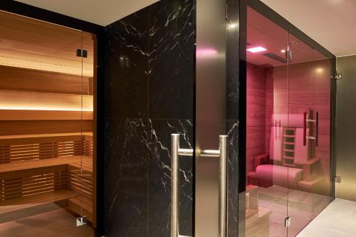 a bathroom with a walk in shower and a glass door at Crystal Hotel superior in St. Moritz