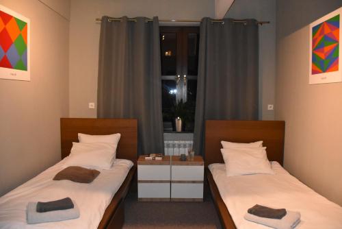two twin beds in a room with a window at Manufaktura Apartamenty Bakery, PRYWATNA KAMIENICA, PARKING STRZEŻONY, KLIMA, DOSTEP NA KOD in Łódź