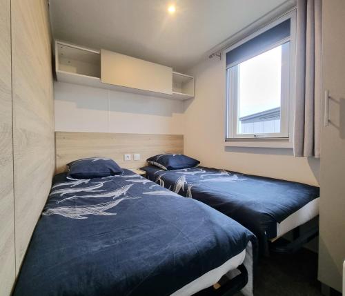 deux lits dans une chambre avec une fenêtre dans l'établissement Mobil home tout confort dans parc résidentiel de loisirs, à Saint-Hilaire-de-Riez