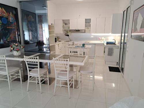 a kitchen with white cabinets and a table and chairs at Villa La Blanca in Pellaro