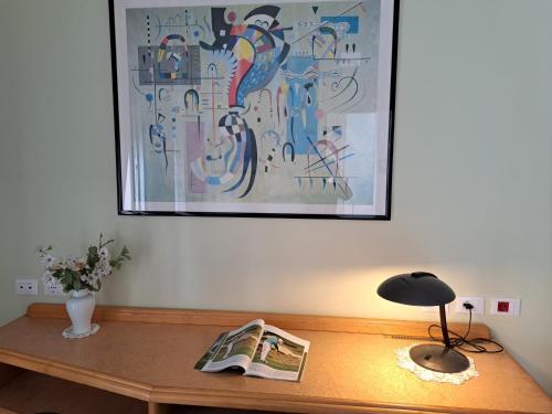 a table with a newspaper and a lamp and a painting at Villa La Blanca in Pellaro