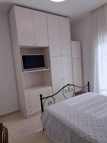 a bedroom with a bed and white cabinets and a tv at Villa La Blanca in Pellaro
