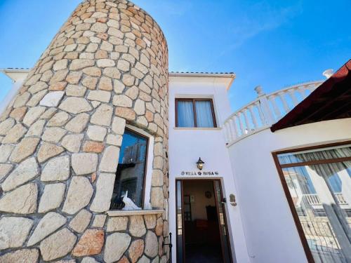 a white house with a large stone wall at Villa Rosa by HolidayKeys in Kyrenia