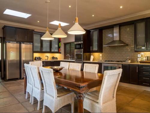 Una cocina con una mesa de madera y sillas blancas. en African Dream Villa, en White River