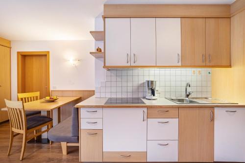a kitchen with white cabinets and a table with a chair at Residence Linderhof in Naz-Sciaves