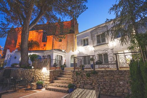 a white house with a stone wall and a tree at Hotel Boutique Palacio De La Duquesa in Ronda