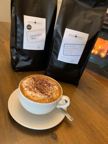 a cup of coffee sitting on a table next to a bag at The Corner House Hotel in Annan