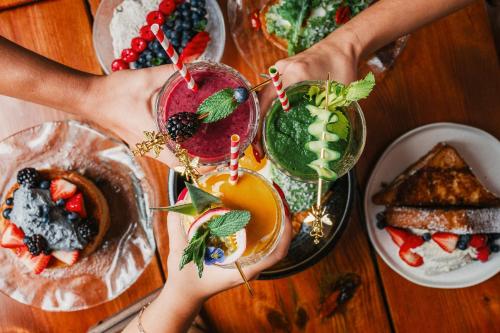 two hands holding drinks on a table with food at Casa Faena Miami Beach in Miami Beach