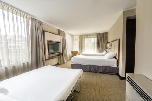 a hotel room with two beds and a flat screen tv at abba Presidente Suites Santiago in Santiago