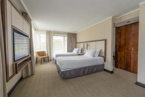 a hotel room with two beds and a flat screen tv at abba Presidente Suites Santiago in Santiago