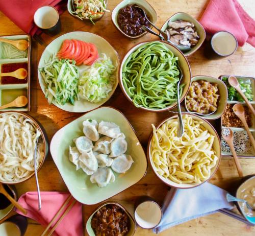 a table topped with bowls of different types of food at Brickyard Retreat at Mutianyu Great Wall Adjoin to Mutianyu Great Wall - Room with the View of Great Wall - Chinese massage experience - Vehicle Shuttle Service - International Catering - SPA& Nail Beauty Facilities in Huairou