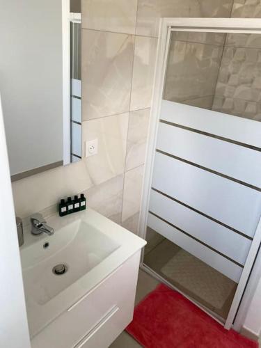 une salle de bain blanche avec une douche et un lavabo dans l'établissement Magnifique MAISON de 80m2, proche CDG & PARIS, à Bonneuil-en-France