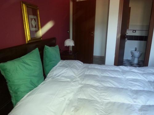 a white bed with green pillows in a bedroom at Il GIARDINACCIO Agriturismo in LʼAquila