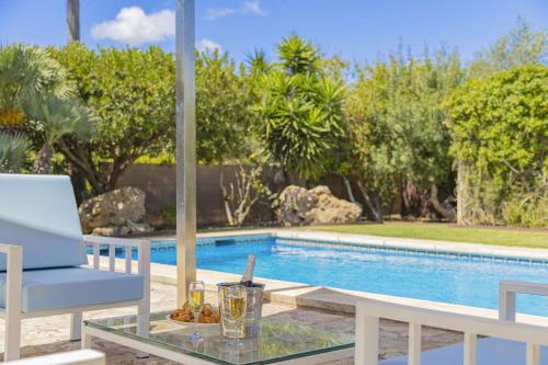 a table and a chair next to a swimming pool at Villa Biel in Pollença